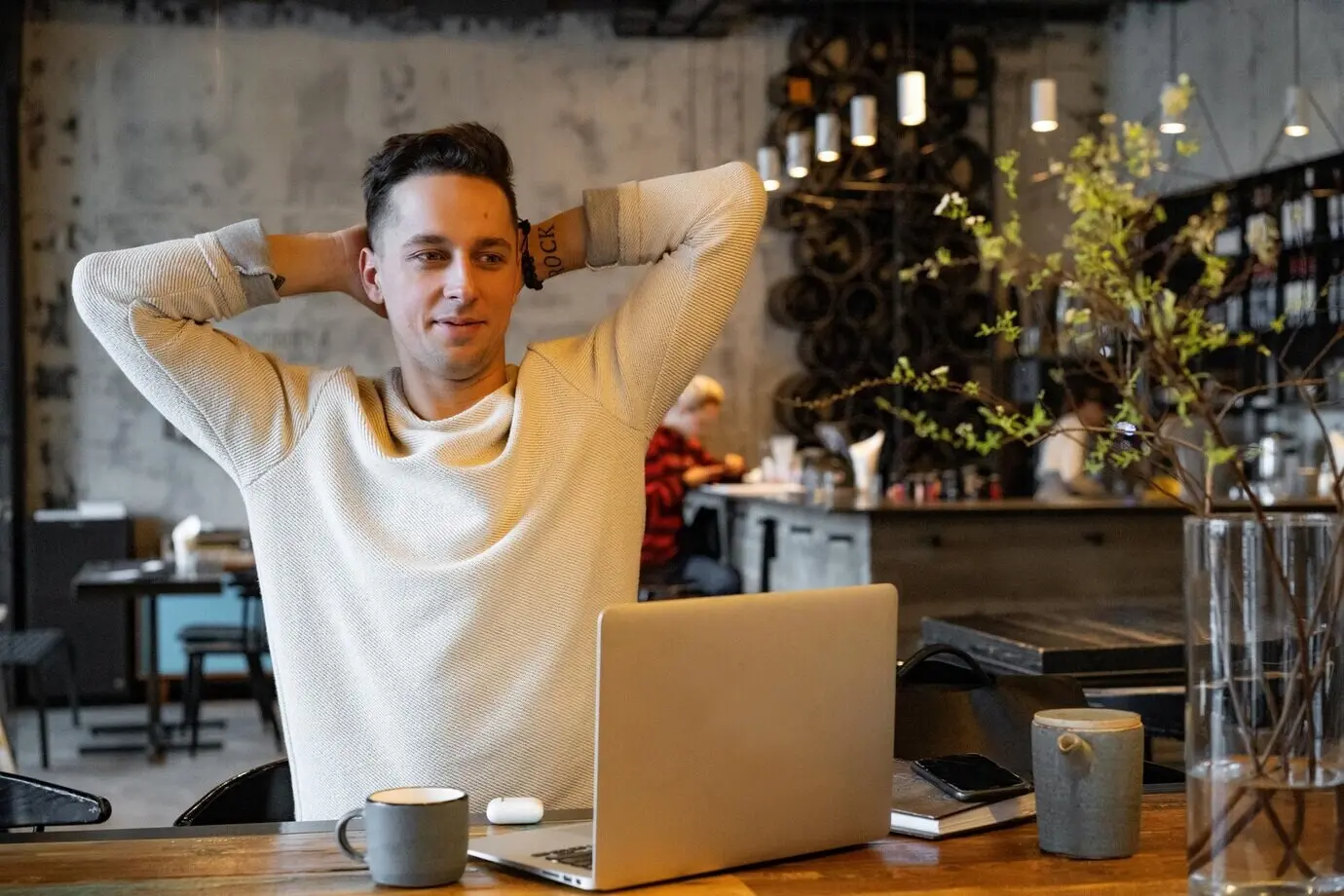 a young man drinking tea and working on a laptop, a freelancer working in a cafe